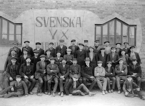 Svenska Yxfabriken. Arbetare med chef sittande utanför fabriken.